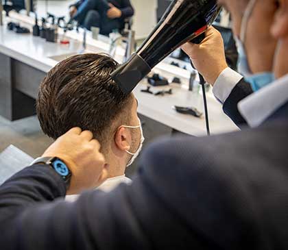parrucchiere passa all'asciugatura capelli dopo il taglio