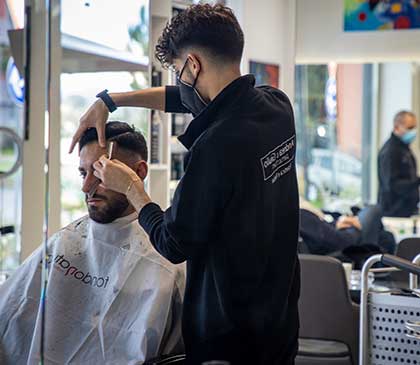 parrucchiere realizza un taglio maschile con la rasatura a lama