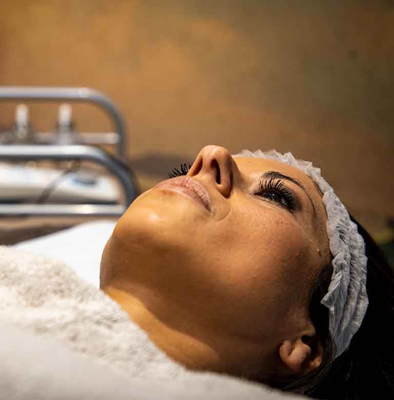 volto di una donna distesa su un lettino che sta per sottoporsi ad un trattamento di radiofrequenza