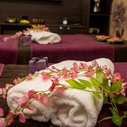 due lettini per massaggi paralleli sui quali sono poggiati due teli e dei fiori