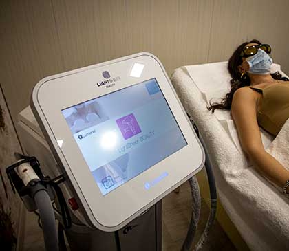 macchinario Lightsheer in primo piano e donna in attesa di un trattamento di epilazione laser sullo sfondo