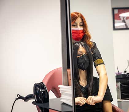 parrucchiera applica un prodotto styling sui capelli di una cliente