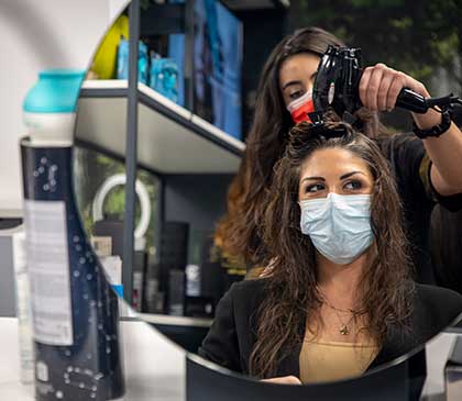 ragazza riflessa nello specchio mentre le viene fatta la messa in piega