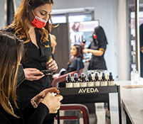 parrucchiera spiega i benefici dei prodotti Aveda ad una cliente del salone