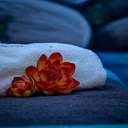 due fior di loto finti e un telo piegato su un lettino del centro estetico di Andrea & Giulio Hair and Relax