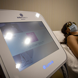 macchinario Lumenis per l'epilazione laser e donna in attesa del trattamento sullo sfondo