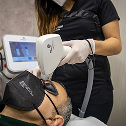 estetista esegue epilazione laser su un viso maschile